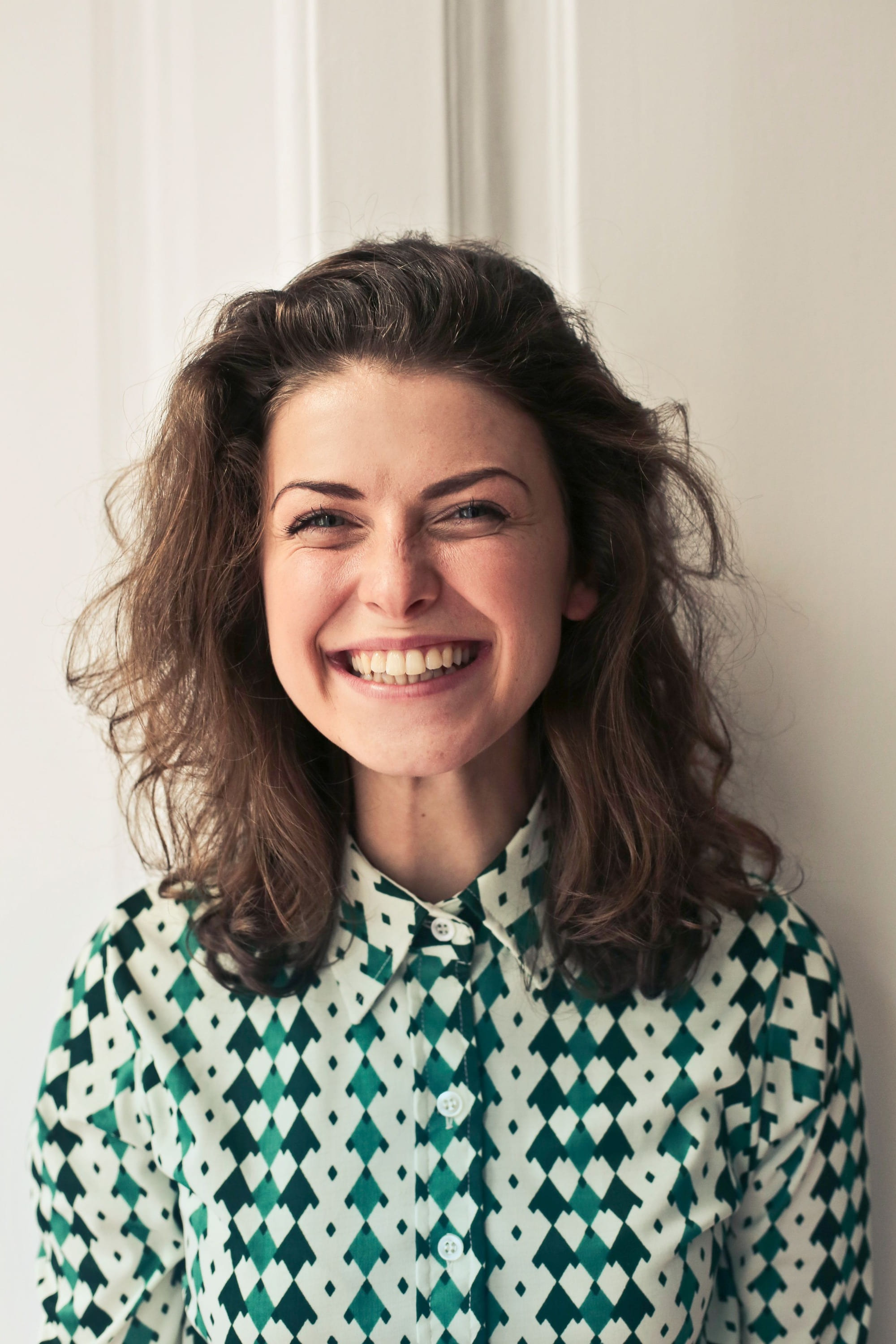 A woman laughing, head turned, in a patterned blouse