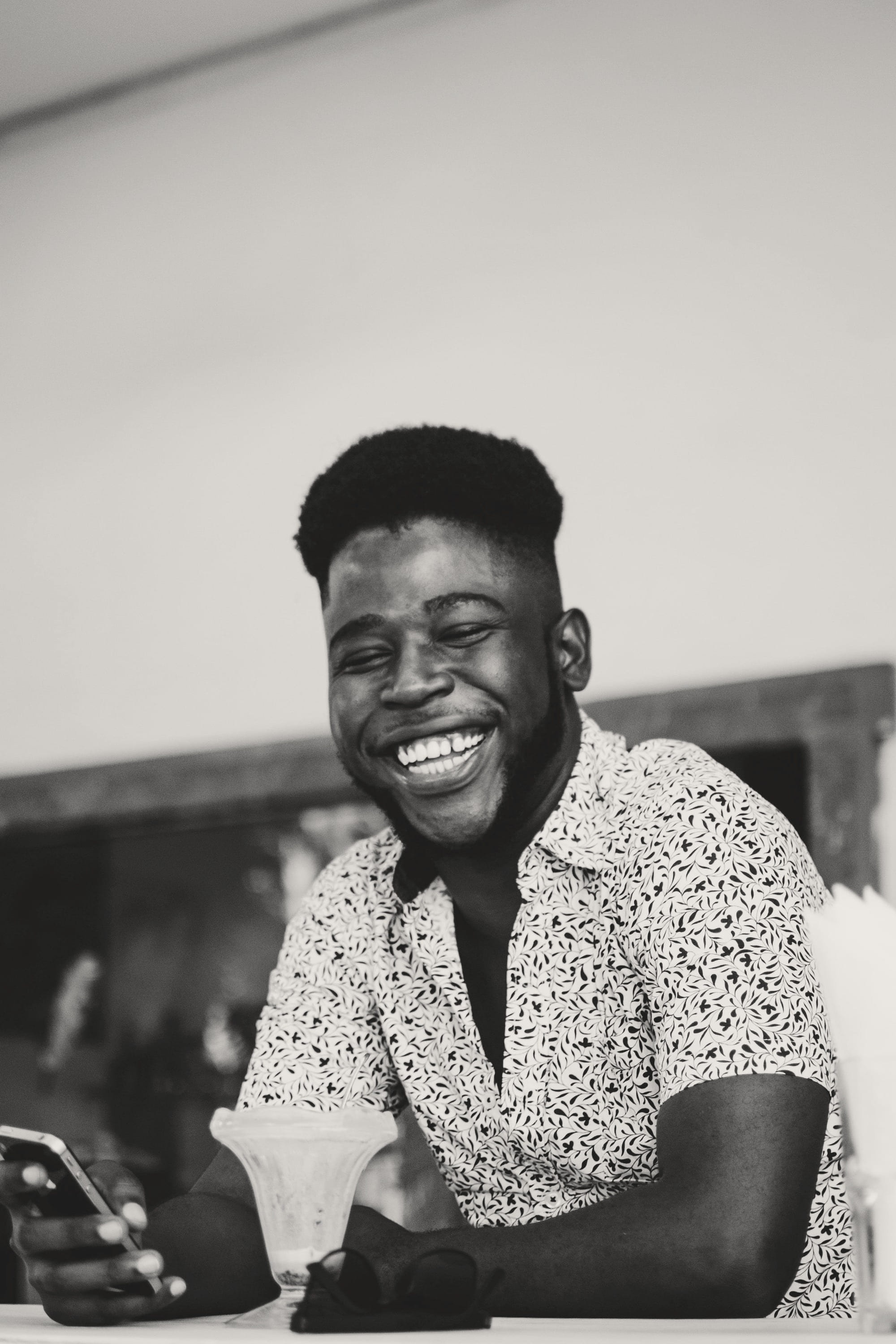 A man laughing at a counter, phone in hand