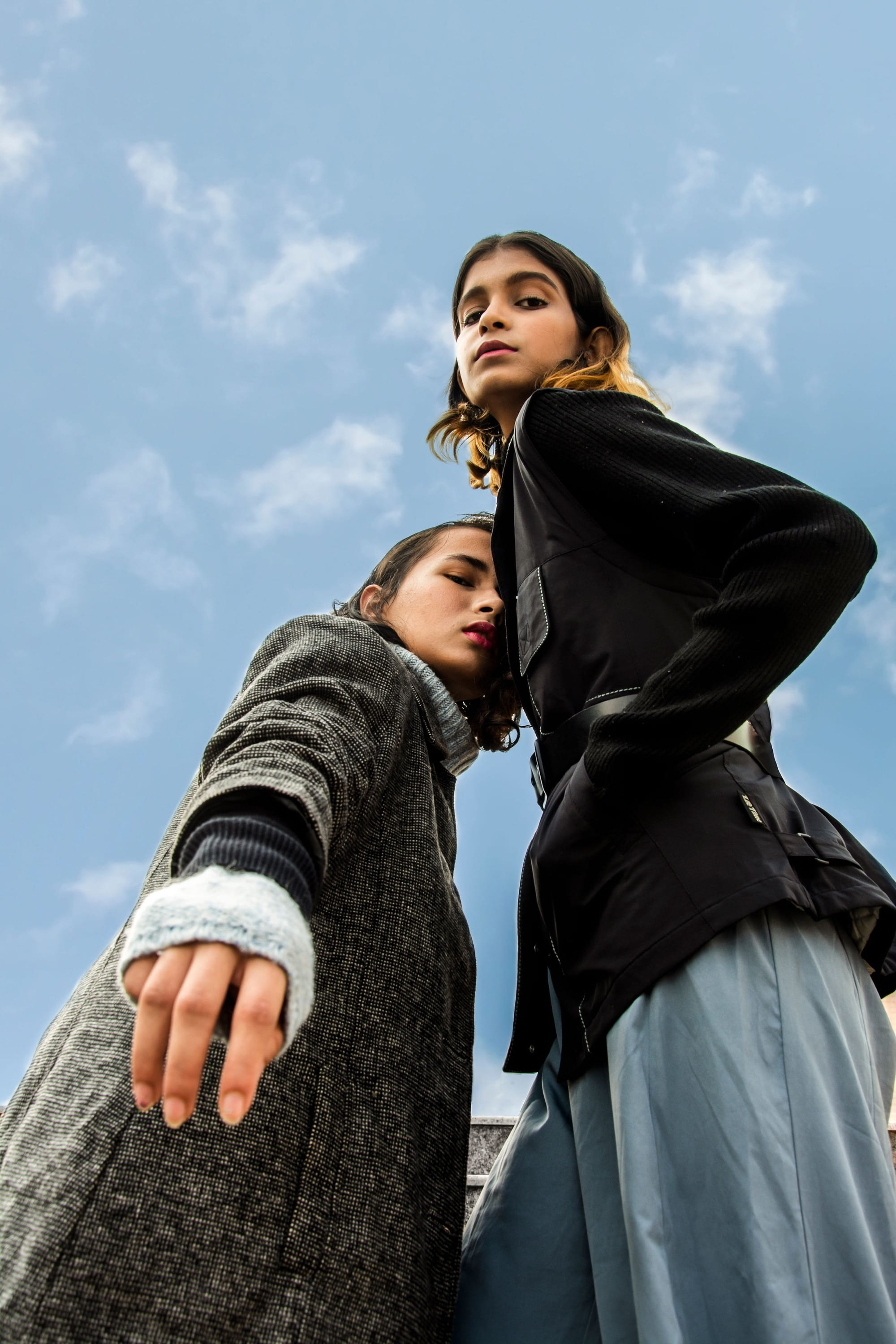 Two friends seen from below against a blue sky
