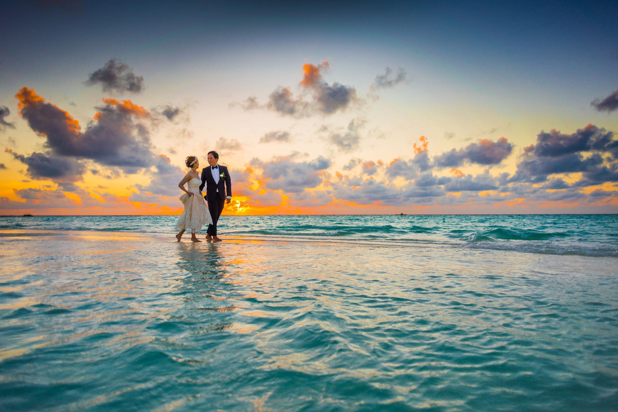 A couple standing in the surf at sunset