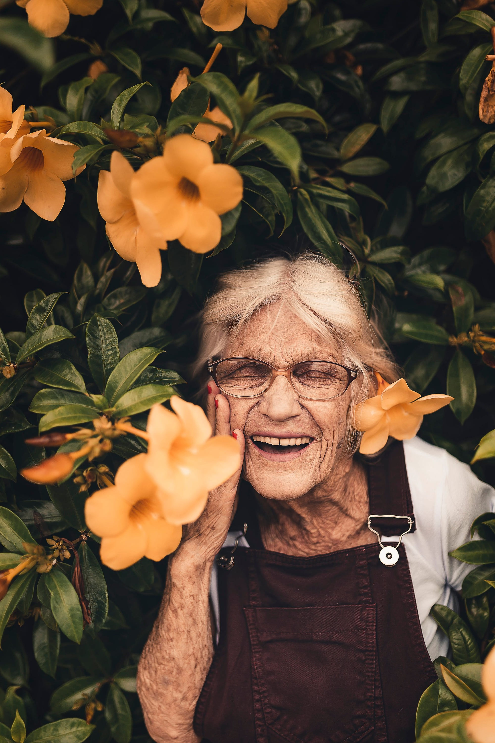An older woman laughing among orange flowers
