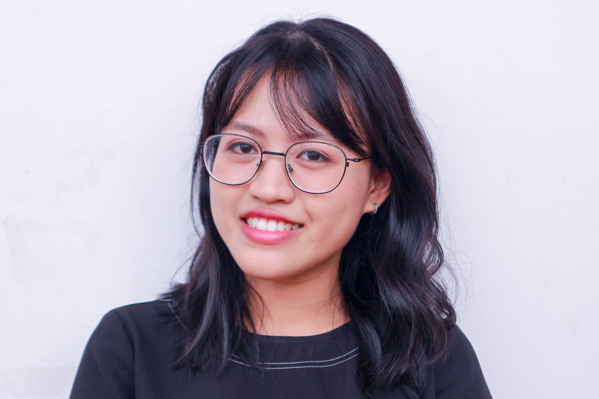 A young woman in glasses, smiling softly