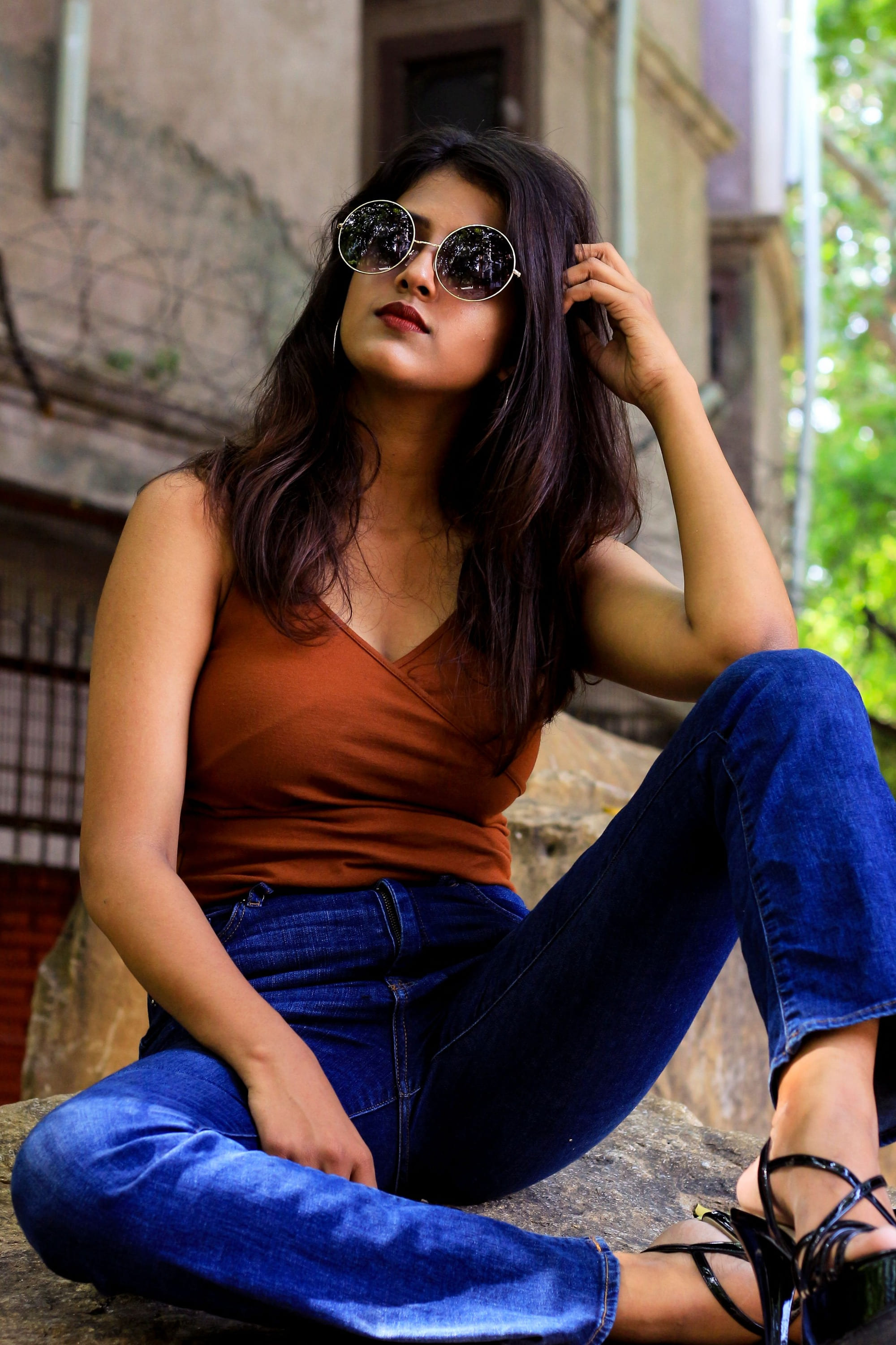 A woman sitting on a doorstep in sunglasses