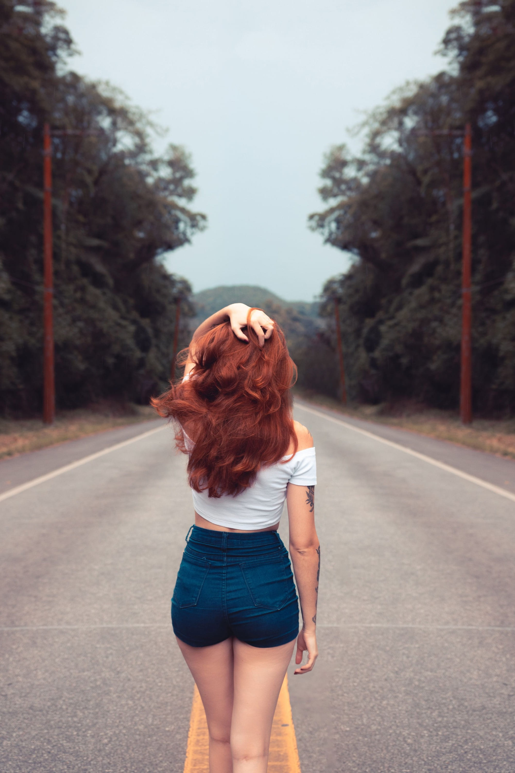 A woman with red hair walking away down an empty road