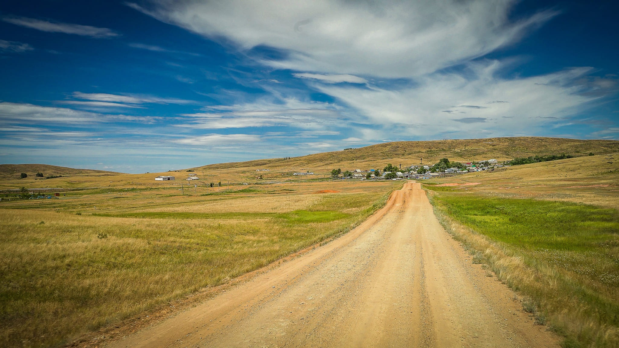 A dirt road running straight into open steppe under a wide sky